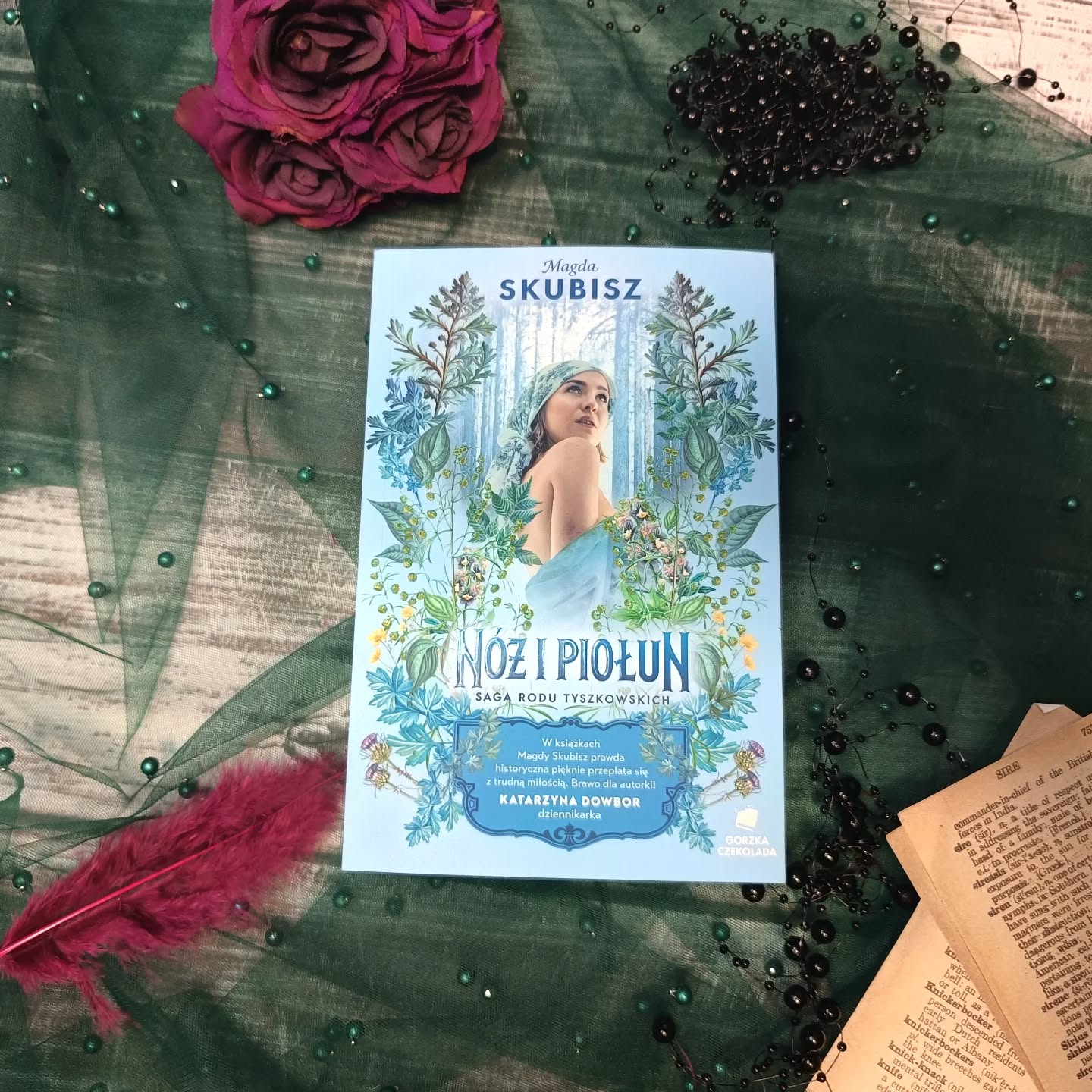 ✍️📖Życie bywa spokojne lub malowane szaleństwem. Miłość buduje i rani, a szczęście miesza się z zapachem niepewności i ziół. Czy dwa odrębne światy mogą się połączyć, a szczęśliwy koniec jest pisany każdemu? Nóż i piołun to wir wydarzeń, w którym ciągłe przeszkody sprawiają, że relacje są skomplikowane, jednak nie należy odpuszczać w swych dążeniach. Antoni wie o tym, jak nikt inny. Czy jego zaloty w stronę Katji w końcu przyniosą skutek? Czy ona przestanie pchać się w kłopoty?

Nóż i piołun

To już piąta odsłona sagi rodu Tyszkowskich i przygoda wciągająca niczym niejedno leśne bagno. To sprawdzona mieszanka humoru, genialnych dialogów i niesamowitych kreacji postaci. Całość składa się na świat, w którym miłość jest niezwykle bolesna, ciężka i często niemożliwa. To zderzenie dwóch biegunów, bogactwa i biedy, miłości i nienawiści. Nóż i piołun podobnie jak i reszta serii napisana jest lekkim i porywającym językiem. Ta opowieść wciąga bez reszty i wprowadza czytelnika w niezwykły stan. Strona po stronie przepadasz w słowach, miejscach i ludziach, których stworzono tak, by z łatwością przemówili do twej duszy.
📖✍️

#wspolpracarecenzencka #gorzkaczekolada #nóżipiołun #magdaskubisz #sagarodutyszkowskich